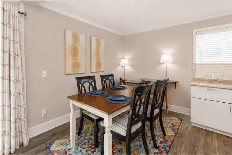 A dining room features a wooden table, four black chairs, and a colorful area rug — 1802 CHAMBERLIN STREET UNIT 2, ORLANDO, FL