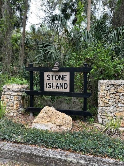 A black wooden sign reading Stone Island stands between two stone pillars in a wooded area — 1747 TURTLE HILL ROAD, DELTONA, FL
