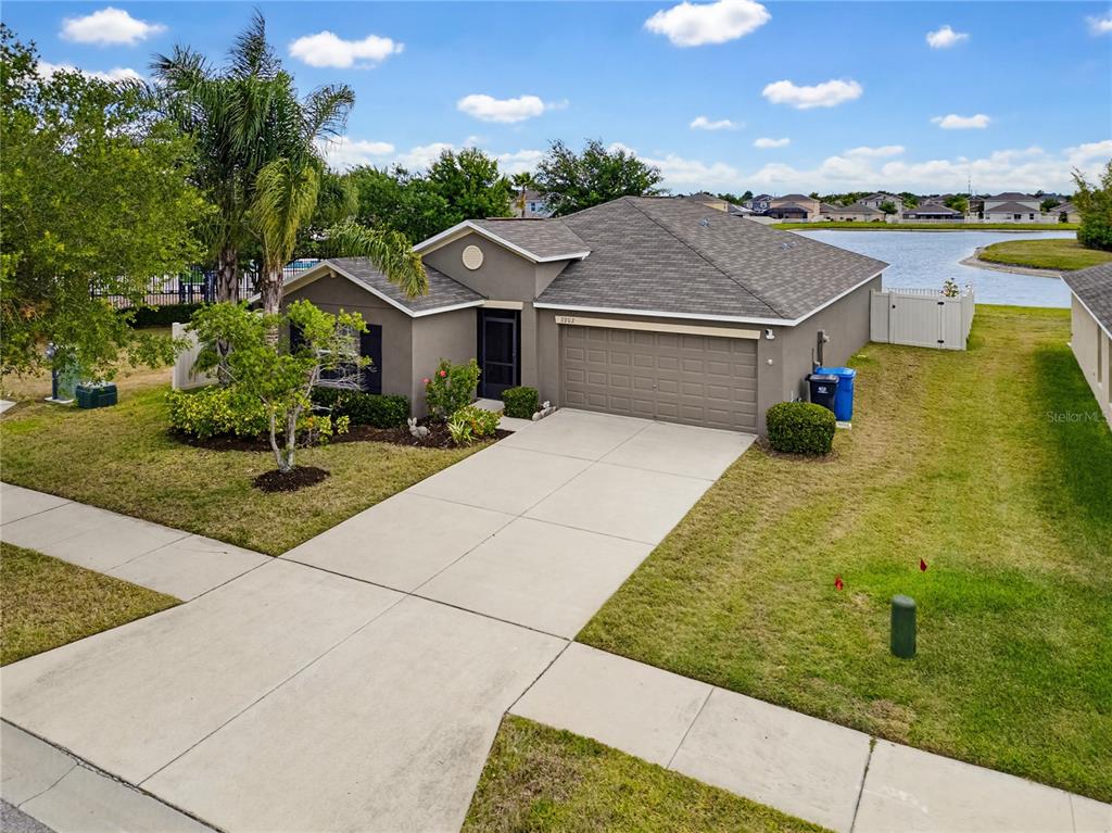An elevated view of a single-story house with a concrete driveway and a backyard lake — 2202 4TH STREET SW, RUSKIN, FL