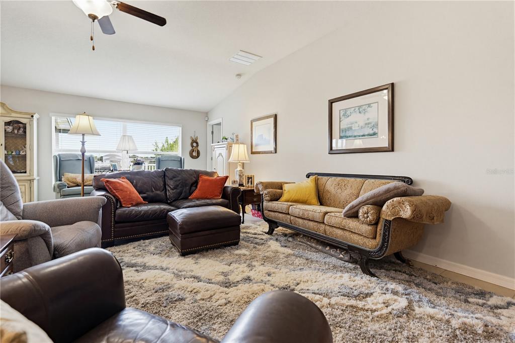 A living room features a leather sofa, a patterned sofa, and a textured area rug — 2202 4TH STREET SW, RUSKIN, FL