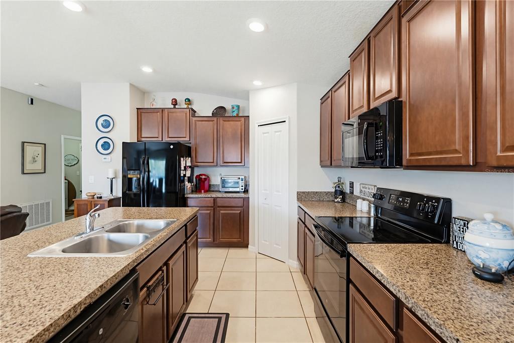 A kitchen features dark wood cabinets, granite countertops, black appliances, and a central island — 2202 4TH STREET SW, RUSKIN, FL