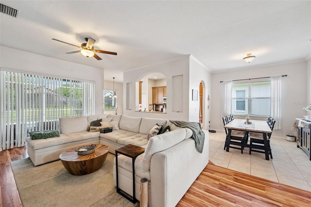 A living room with a sectional sofa and coffee table opens to a dining area — 4641 ROLLING GREEN DRIVE, WESLEY CHAPEL, FL
