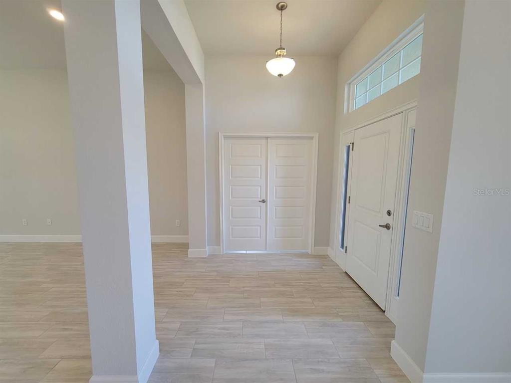 An entryway features light-colored tile flooring, a white double door, and a pendant light fixture — 16464 SW 54TH COURT ROAD, OCALA, FL