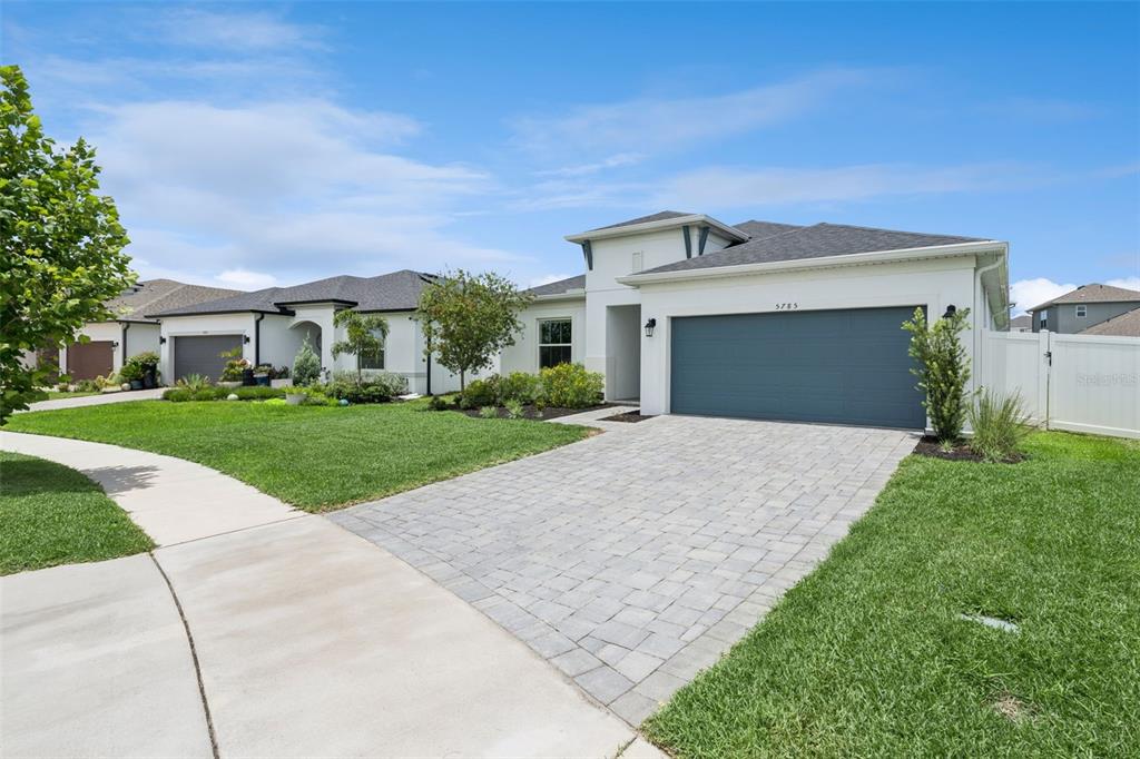 A modern single-story house with a paved driveway, two-car garage, and a manicured front lawn — 5785 WALLIS LANE, ST CLOUD, FL