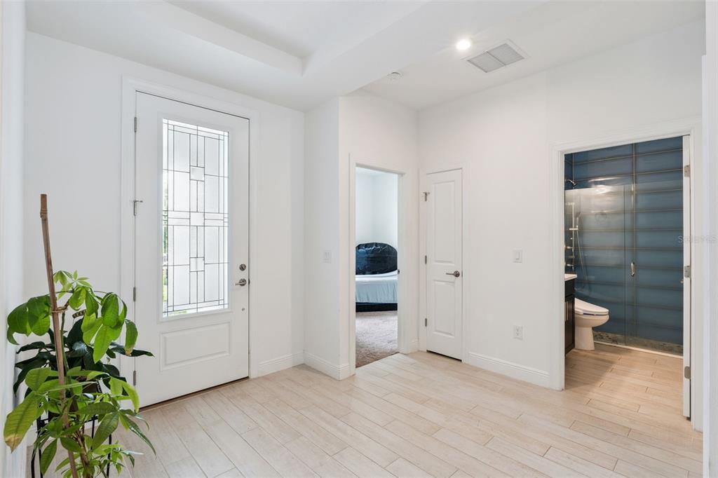 A bright entryway features light wood-look tile flooring, a white front door, and two doorways — 5785 WALLIS LANE, ST CLOUD, FL