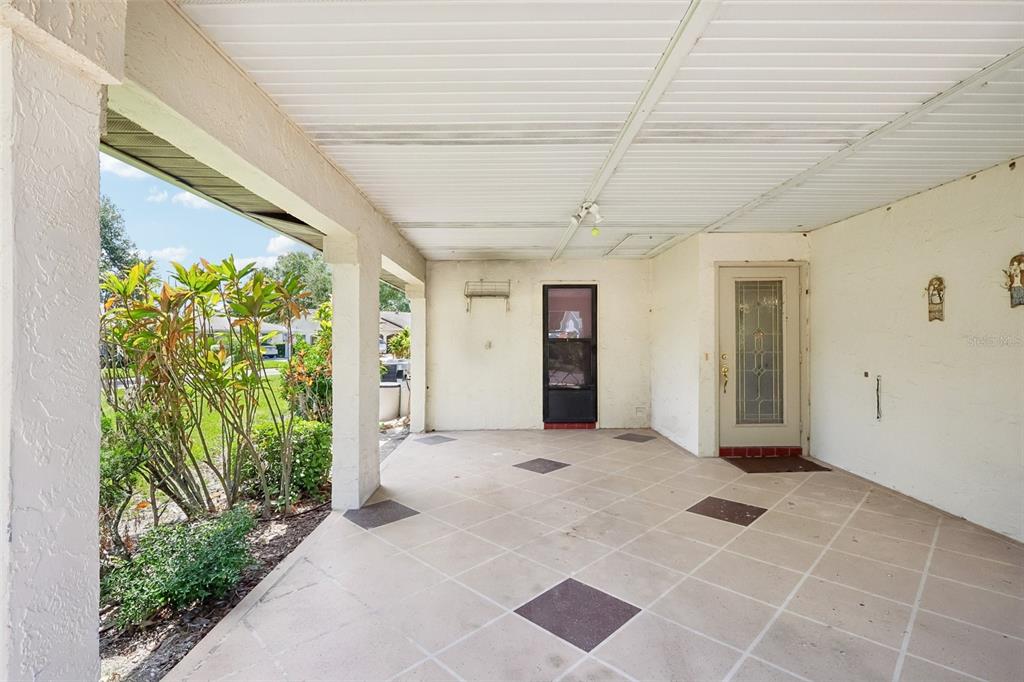 A covered patio with a tiled floor, white walls, and two doors leading inside — 2017 HAMPSTEAD CIRCLE, SUN CITY CENTER, FL