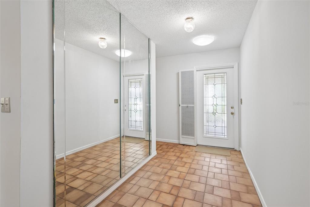 An entryway features tiled flooring, a mirrored wall, and a white door with glass panels — 2017 HAMPSTEAD CIRCLE, SUN CITY CENTER, FL