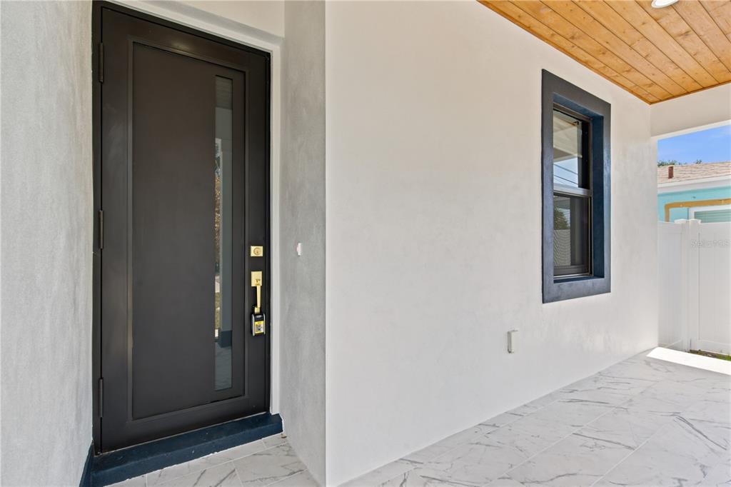 A modern front porch features a dark door, a window with dark trim, and tiled flooring — 1121 ENGMAN STREET, CLEARWATER, FL