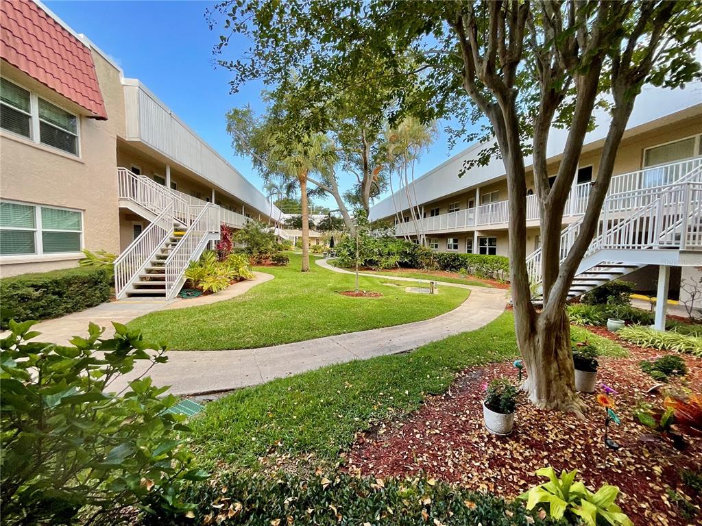 A living room features light green walls, tile flooring, floral furniture, and a ceiling fan — 10034 64TH AVENUE N UNIT 11, ST PETERSBURG, FL