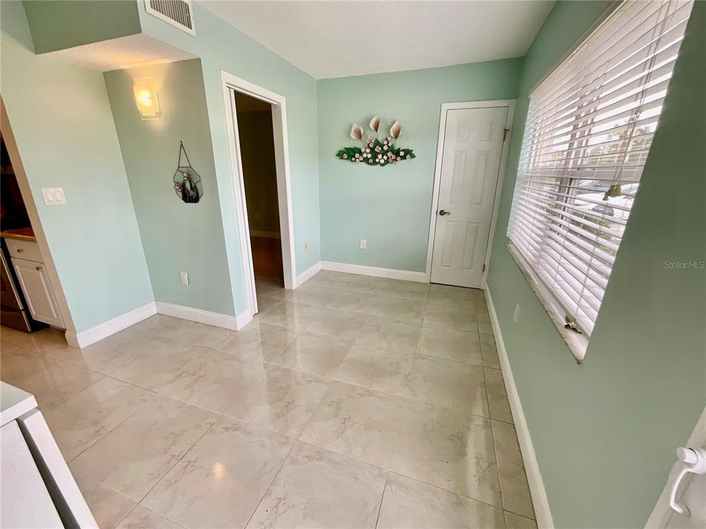 A living room features light blue walls, tile flooring, floral furniture, and a ceiling fan — 10034 64TH AVENUE N UNIT 11, ST PETERSBURG, FL