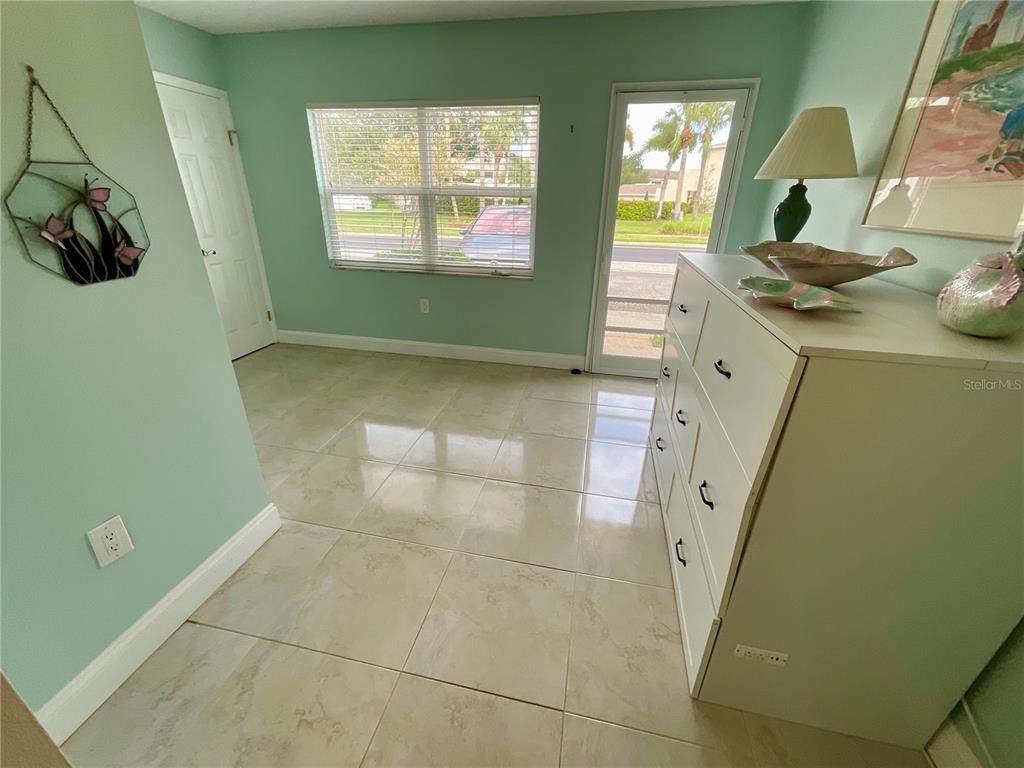 A living and dining area features light green walls, tile flooring, and pastel-colored furniture — 10034 64TH AVENUE N UNIT 11, ST PETERSBURG, FL