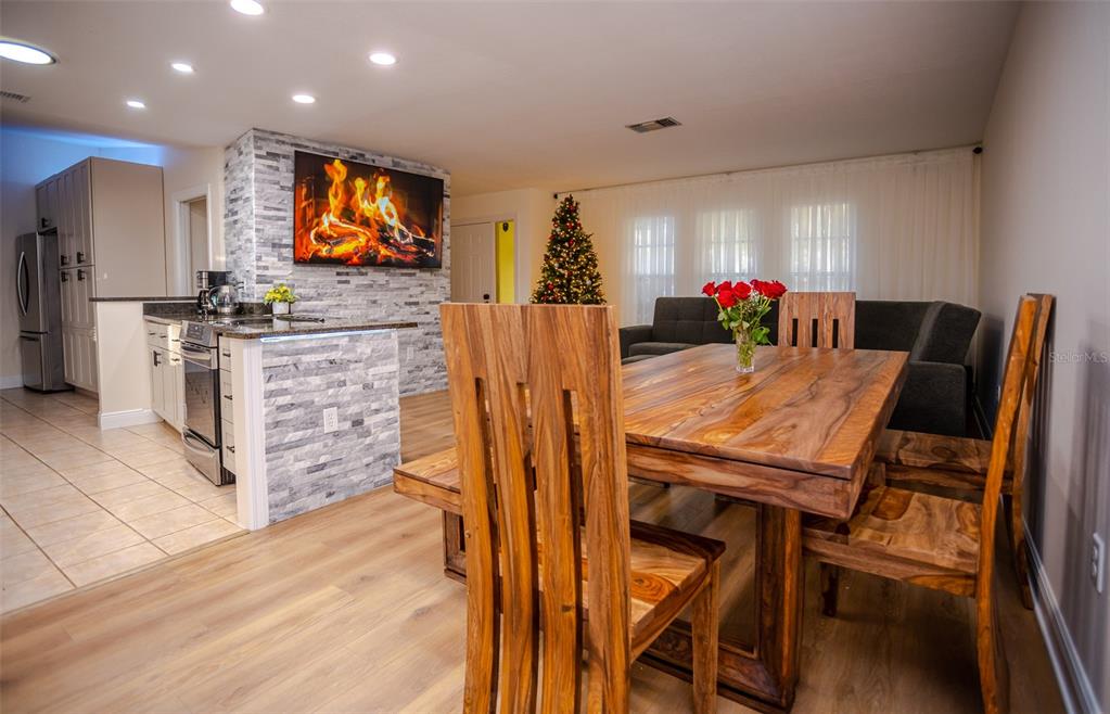 A dining area with a wooden table and chairs sits adjacent to a stone-accented kitchen — 2719 FOREST KNOLL DRIVE, SARASOTA, FL