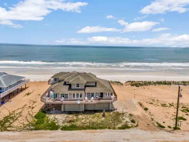 An elevated beachfront house with a wrap-around deck sits on a sandy lot by the ocean — 9353 OLD A1A, ST AUGUSTINE, FL