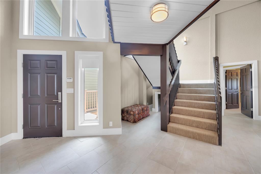 An entryway features tile flooring, a dark front door, a carpeted staircase, and a patterned bench — 9353 OLD A1A, ST AUGUSTINE, FL