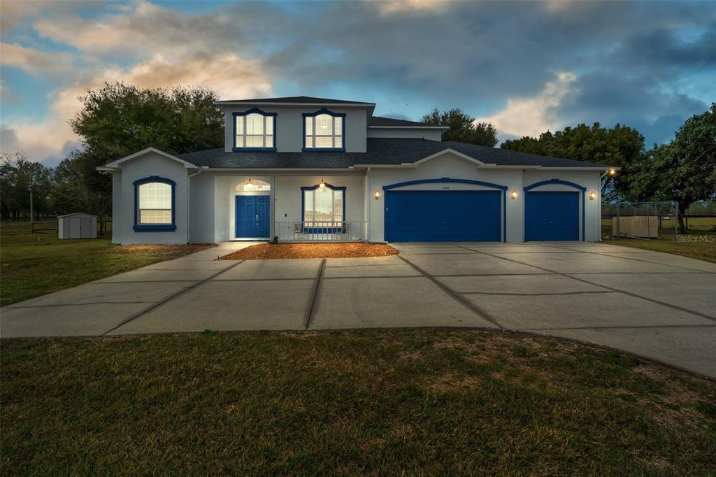 A two-story house with a blue garage, blue front door, and a large concrete driveway — 13496 S OAKVIEW AVENUE, FLORAL CITY, FL