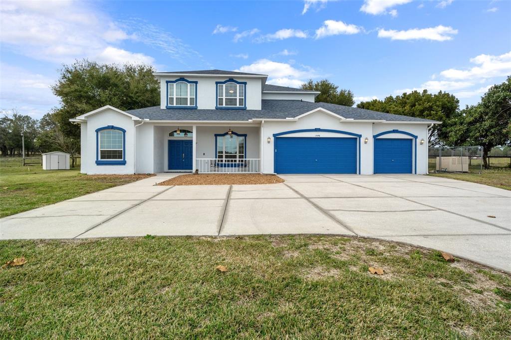 A two-story house with white stucco walls, blue trim, and a three-car garage — 13496 S OAKVIEW AVENUE, FLORAL CITY, FL