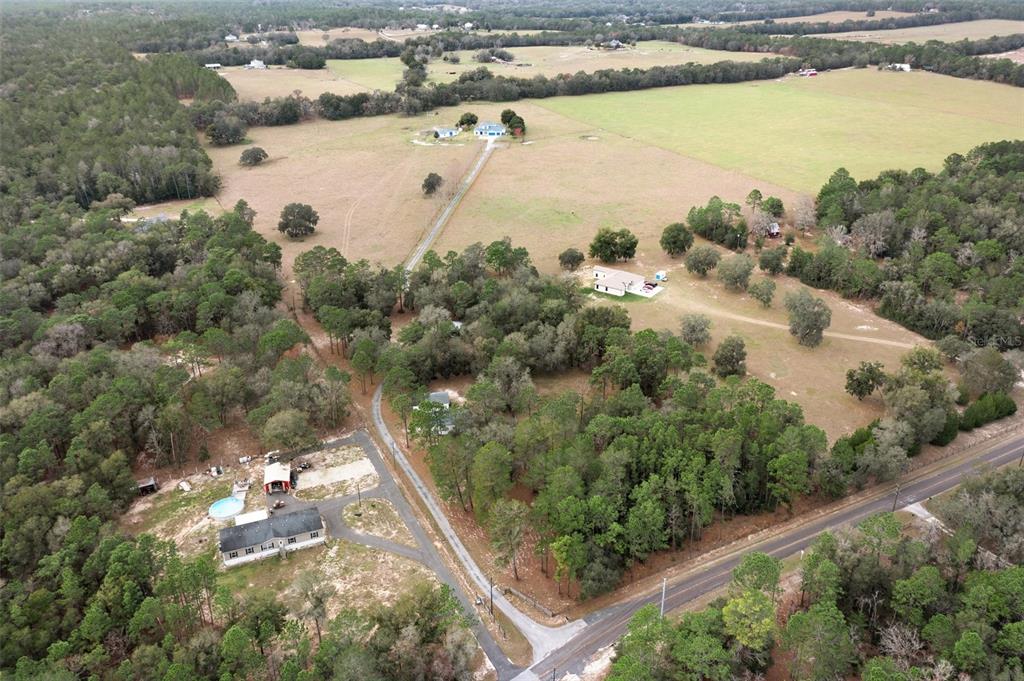 An aerial view shows a rural property with multiple houses, open fields, and wooded areas — 13496 S OAKVIEW AVENUE, FLORAL CITY, FL