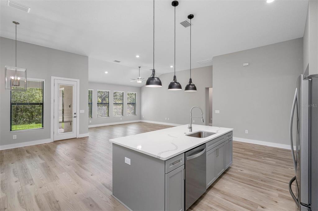 A kitchen island with a sink and pendant lights overlooks an open-concept living area — 13063 OLDENBURG DRIVE, HUDSON, FL