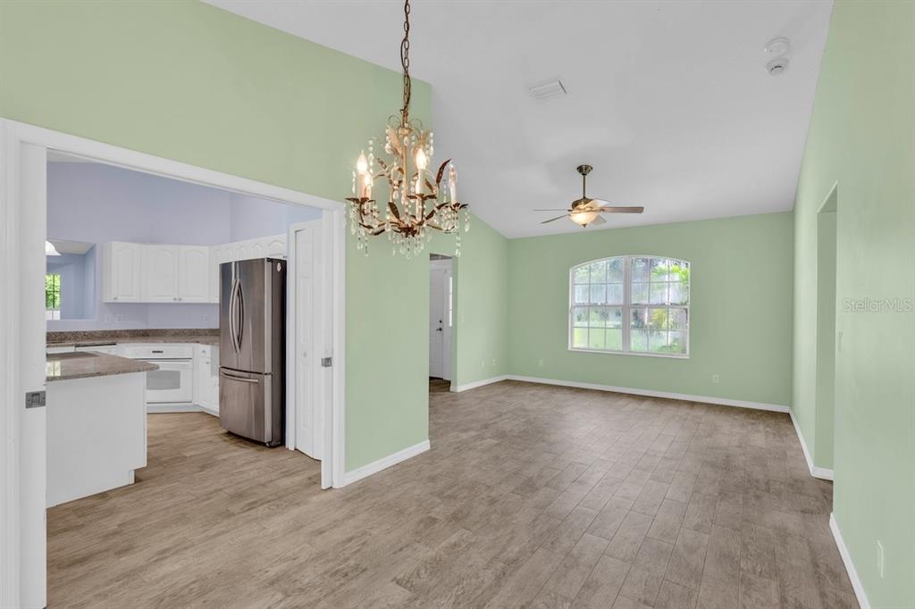 A living room with light green walls, wood-look tile flooring, and an arched window — 821 ROBIN LANE, SEBASTIAN, FL
