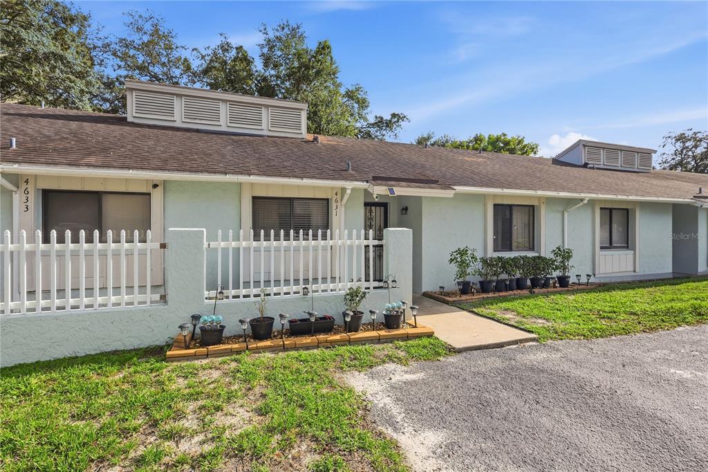 A light blue single-story building features a white picket fence and a gravel driveway — 4631 N PINE HILLS ROAD UNIT 110, ORLANDO, FL