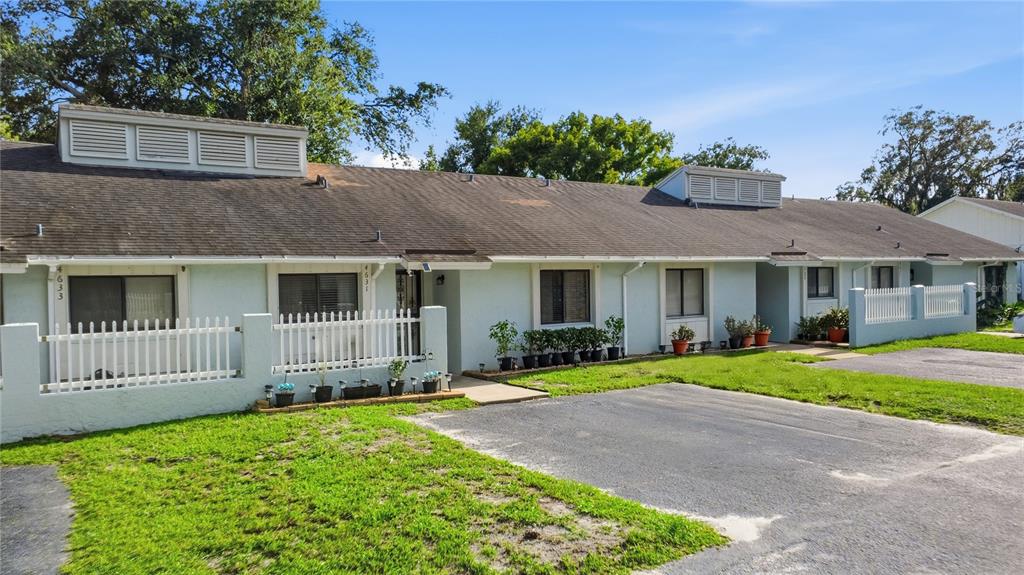 A single-story multi-unit building with light blue stucco walls, white picket fences, and asphalt parking — 4631 N PINE HILLS ROAD UNIT 110, ORLANDO, FL