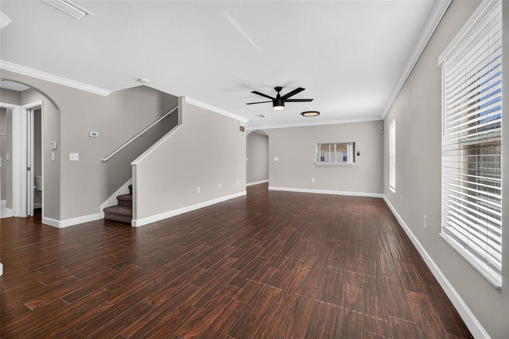 An empty living room features dark wood-look tile flooring, gray walls, and a staircase — 10629 SHADY PRESERVE DRIVE, RIVERVIEW, FL