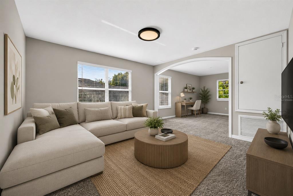 A living room with a sectional sofa, round coffee table, and an arched entryway — 10629 SHADY PRESERVE DRIVE, RIVERVIEW, FL