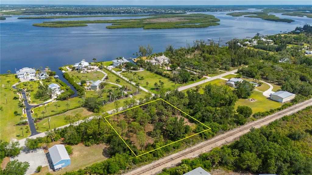 An aerial view shows a rectangular wooded lot outlined in yellow near a waterfront neighborhood — 4685 RIVERSIDE DRIVE, PUNTA GORDA, FL