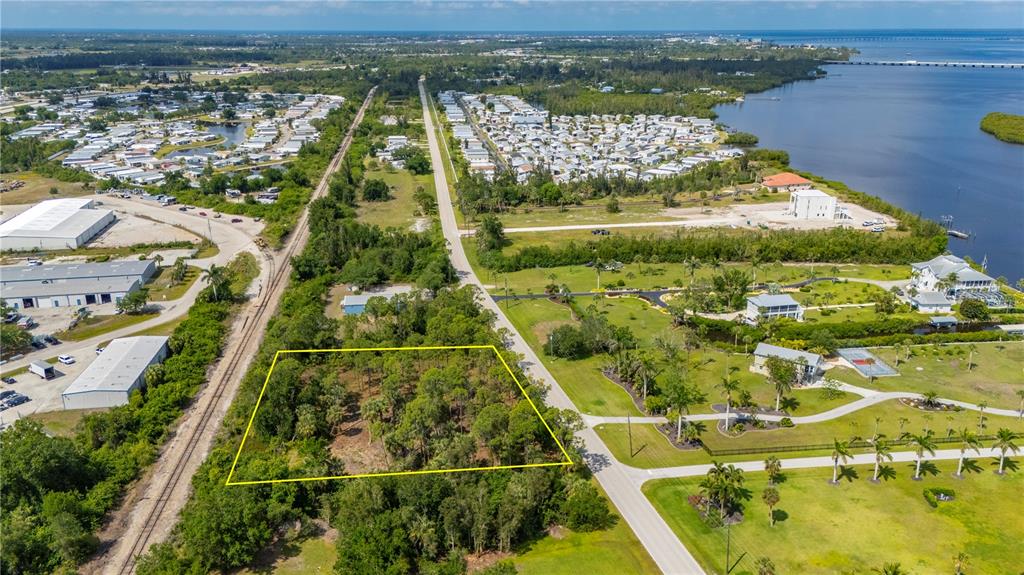 An aerial view shows a wooded, rectangular lot outlined in yellow next to a road — 4685 RIVERSIDE DRIVE, PUNTA GORDA, FL