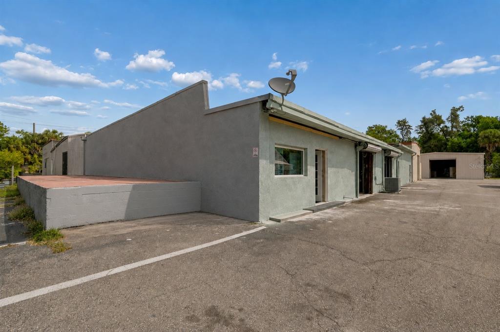 The exterior of a light-colored commercial building features a flat roof, satellite dish, and parking — 4214 W VIRGINIA AVE UNIT 7, TAMPA, FL