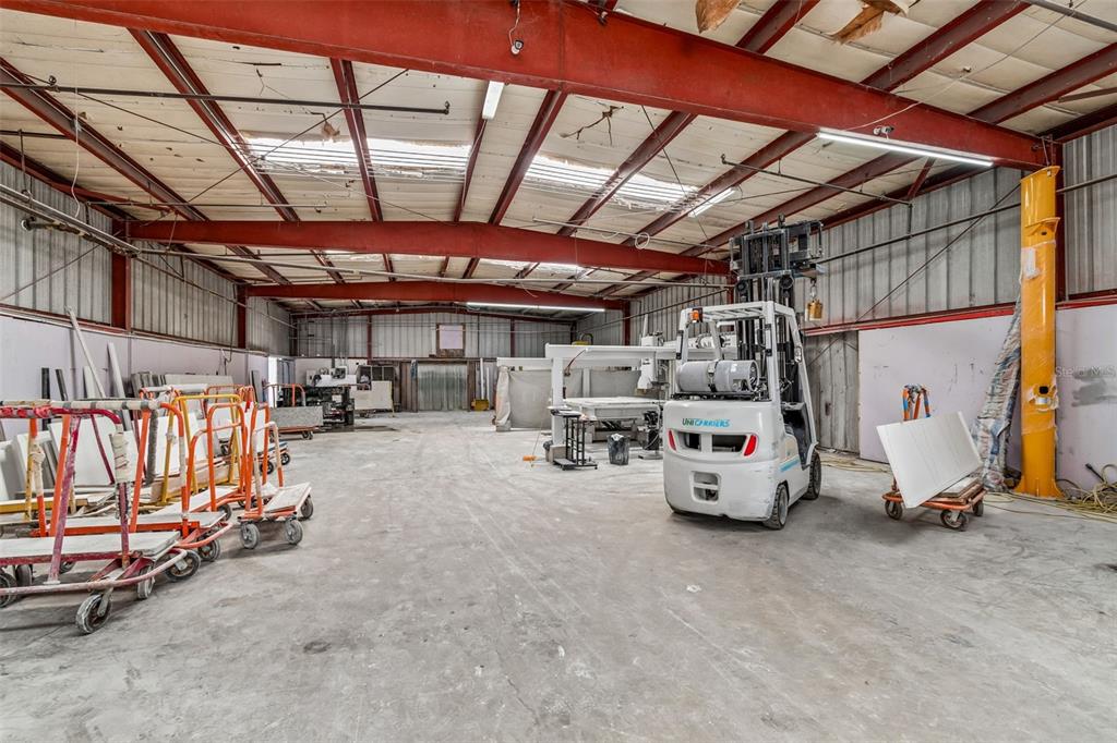 An industrial warehouse interior features a concrete floor, red steel beams, and a white forklift — 4214 W VIRGINIA AVE UNIT 7, TAMPA, FL