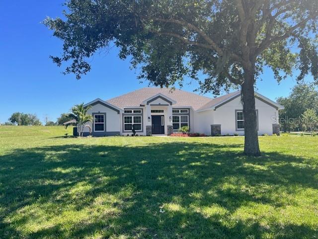 A single-story house with a light-colored exterior, dark trim, and a large front lawn — 37266 HIDDEN VIEW CIRCLE, DADE CITY, FL