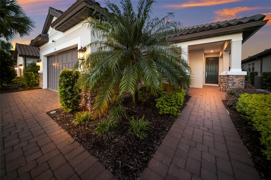 A paved walkway leads to the front entrance of a house with a palm tree — 11112 DEVONBRIDGE DRIVE, PALMETTO, FL