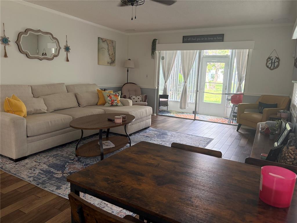 A living room features a sectional sofa, coffee table, and sliding glass doors to a patio — 6002 AMBERLY AVENUE UNIT F, ORLANDO, FL