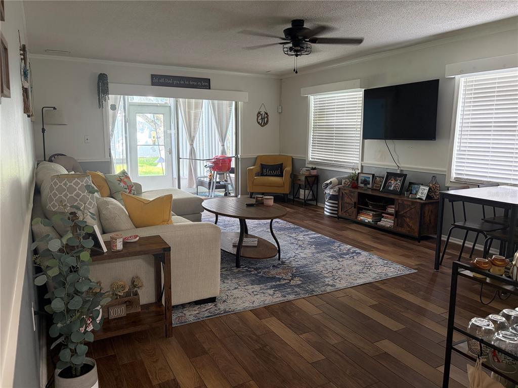 A living room features a sectional sofa, area rug, television, and sliding glass doors — 6002 AMBERLY AVENUE UNIT F, ORLANDO, FL