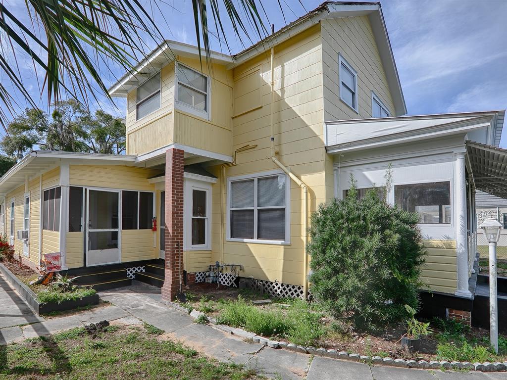 A yellow two-story house with a screened porch, brick pillar, and a stone walkway — 422 E CITRUS AVENUE, EUSTIS, FL