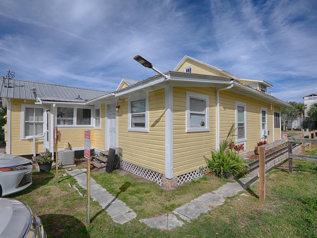 A yellow, single-story house with a metal roof and a wooden fence on the side — 422 E CITRUS AVENUE, EUSTIS, FL