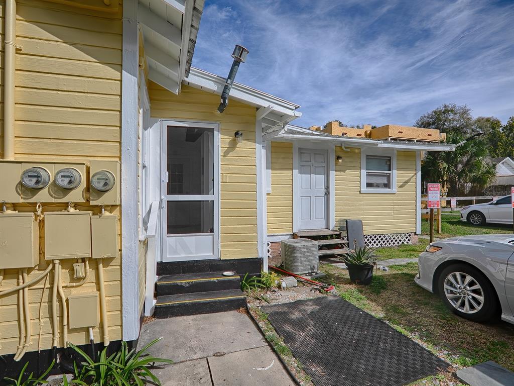 The exterior of a yellow house features two doors, utility meters, and a parking area — 422 E CITRUS AVENUE, EUSTIS, FL