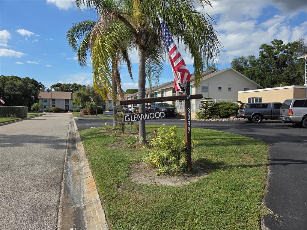 A sign for Glenwood stands in a grassy area with a palm tree and flag — 8039 GARDEN DRIVE UNIT 109, SEMINOLE, FL