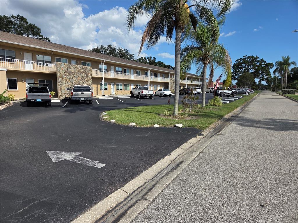 A two-story apartment building features a parking lot with several vehicles and palm trees — 8039 GARDEN DRIVE UNIT 109, SEMINOLE, FL