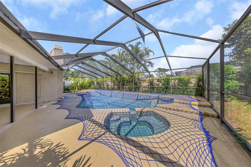 A screened-in pool and spa area with a safety net covering the water — 3582 FAIRWAY FOREST DRIVE, PALM HARBOR, FL