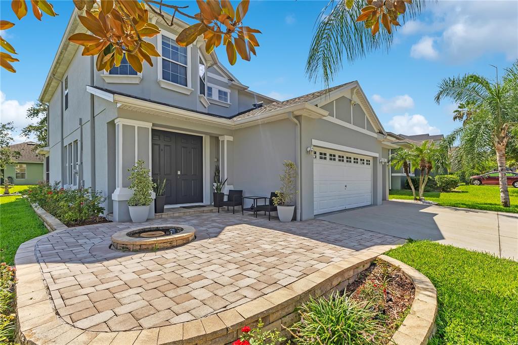 A two-story house features a paved front patio with a fire pit and a garage — 1411 PLUMGRASS CIRCLE, OCOEE, FL