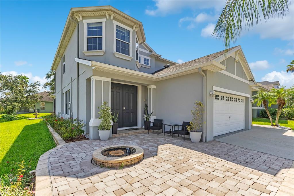 A two-story house exterior features a paved patio, a fire pit, and a garage — 1411 PLUMGRASS CIRCLE, OCOEE, FL