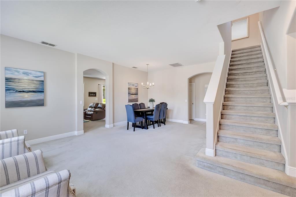 A dining area and carpeted staircase are visible in this open-concept home interior — 1411 PLUMGRASS CIRCLE, OCOEE, FL