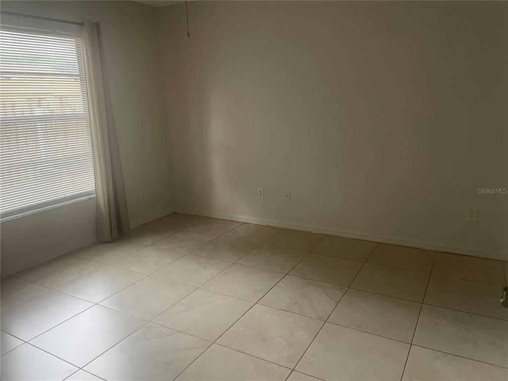 An empty room with light-colored tile flooring, white walls, and a window with blinds — 1349 PIERCE STREET, CLEARWATER, FL