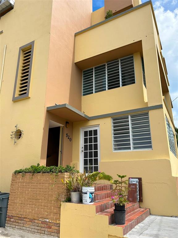 A two-story yellow stucco building features a brick planter, exterior stairs, and louvered windows — 520 RIERA UNIT 3, SAN JUAN, PR