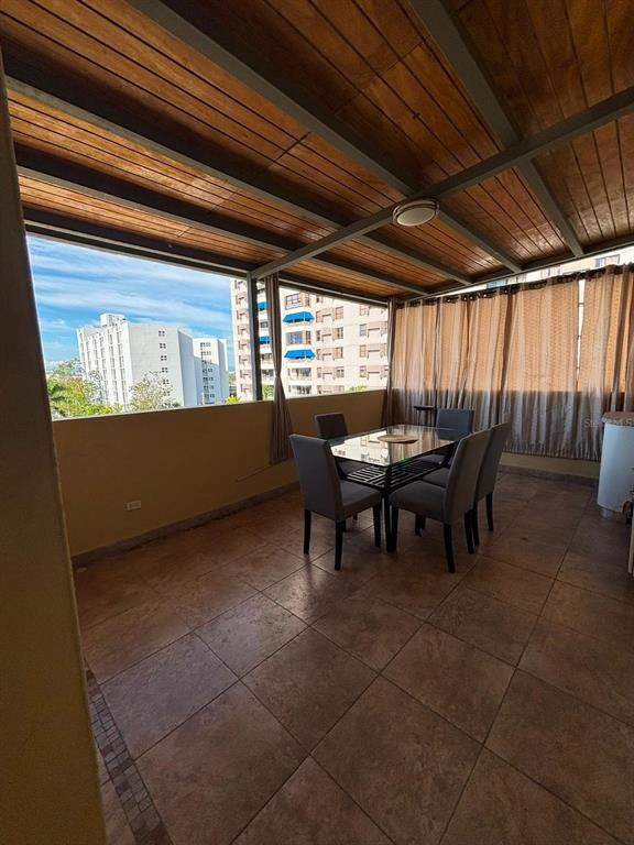 A covered outdoor balcony features a dining set, tile flooring, and views of nearby buildings — 520 RIERA UNIT 3, SAN JUAN, PR