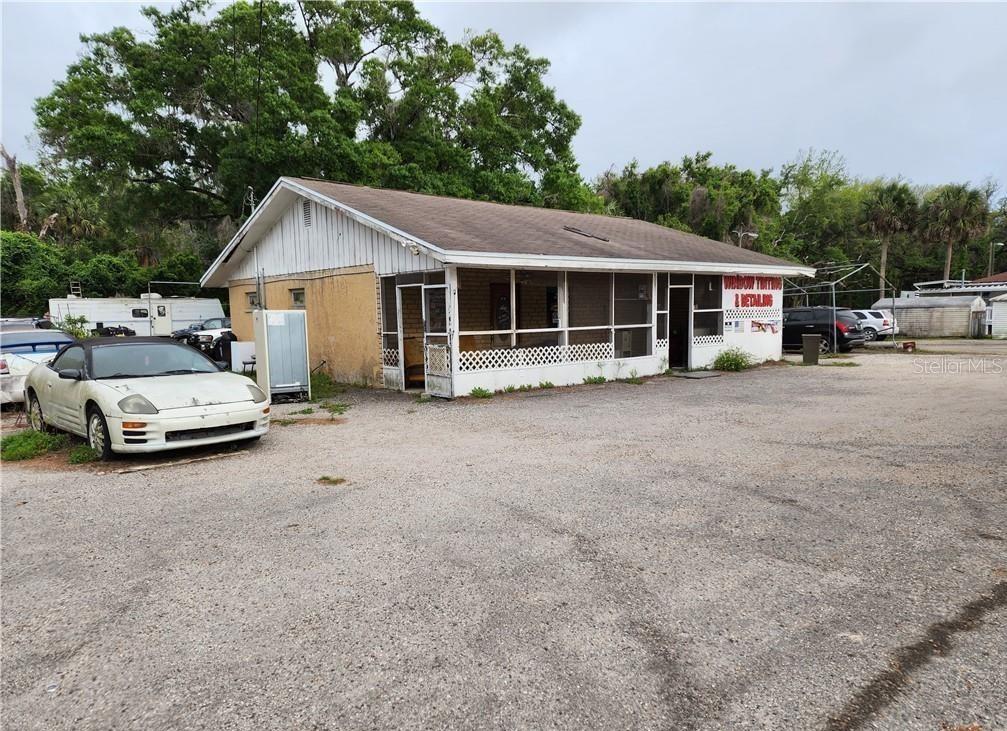 A single-story commercial building with a screened porch and a gravel parking lot — 123 HWY 19, INGLIS, FL