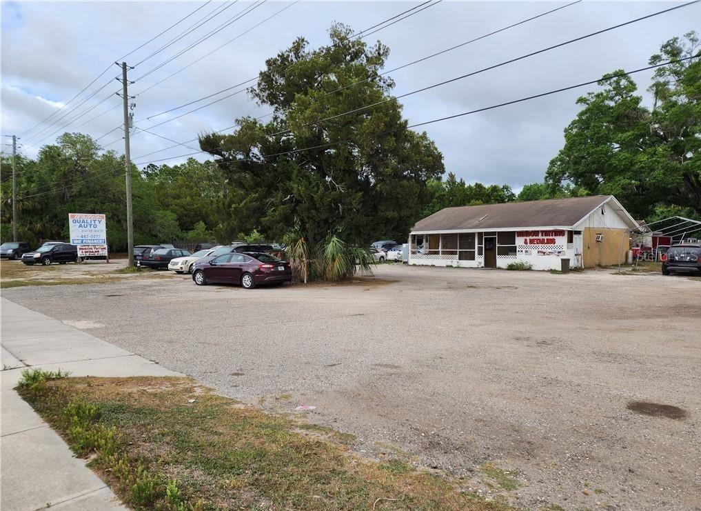 An exterior view of a commercial building with a gravel parking lot and several cars — 123 HWY 19, INGLIS, FL