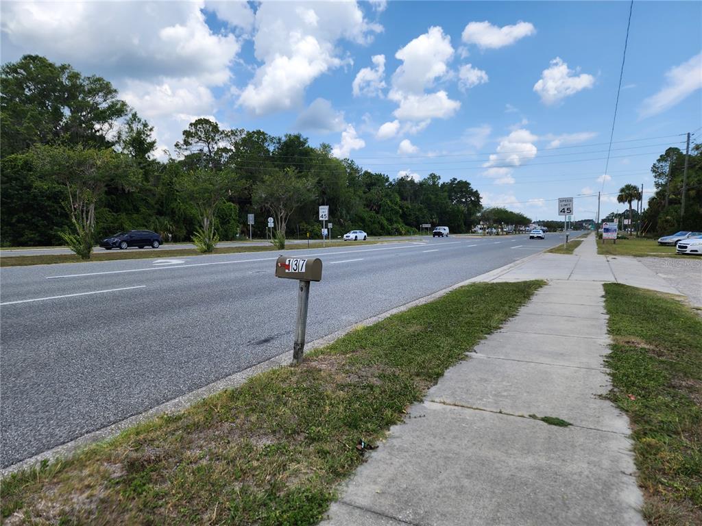 A mailbox labeled 137 stands beside a paved road with a sidewalk and trees nearby — 123 HWY 19, INGLIS, FL